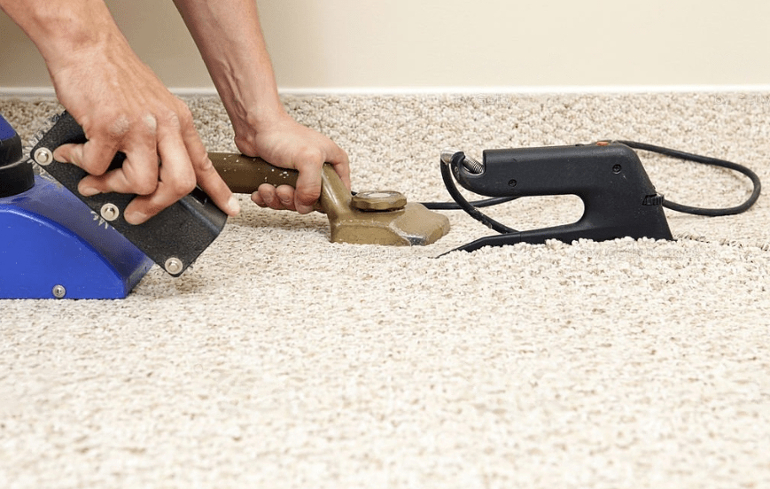 A person using carpet fixer tool to install a carpet 
