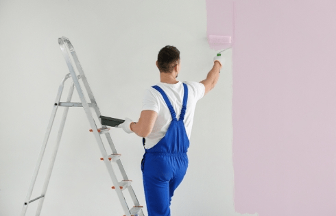 A Men painting the apartment wall with paint roller