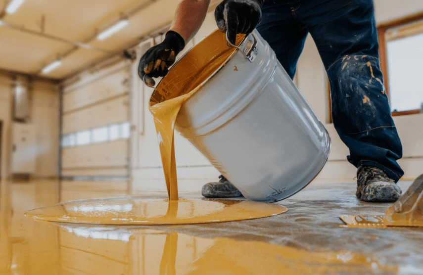 Man having bucket filled with paint doing epoxy flooring