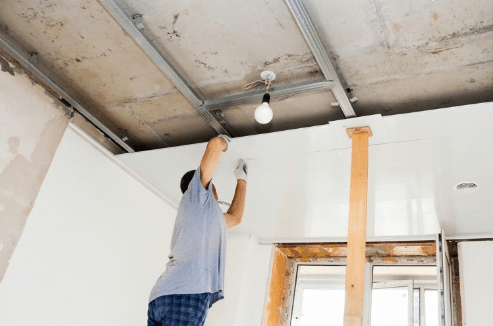 a person working on a ceiling for gypsum partition 